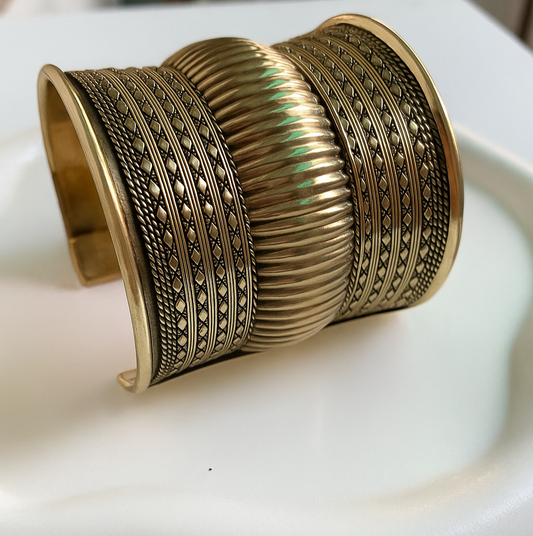 Gold bracelet with intricate patterns on a white surface